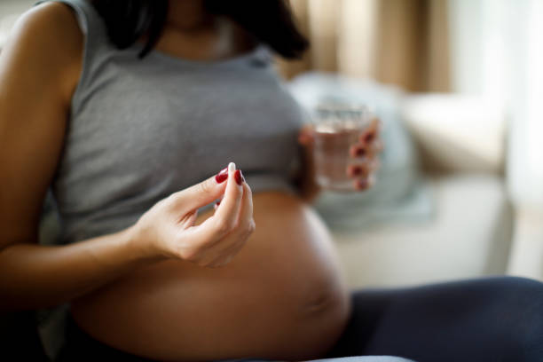 mujer embarazada tomando píldora en casa - vitamin e capsule medicine pill fotografías e imágenes de stock