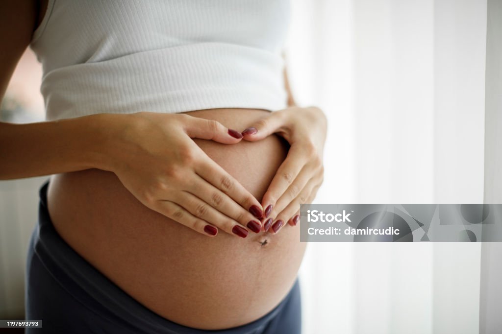 Pregnant woman holding her belly and making a heart shape Pregnant Stock Photo