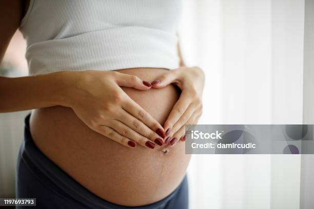 Pregnant Woman Holding Her Belly And Making A Heart Shape Stock Photo - Download Image Now