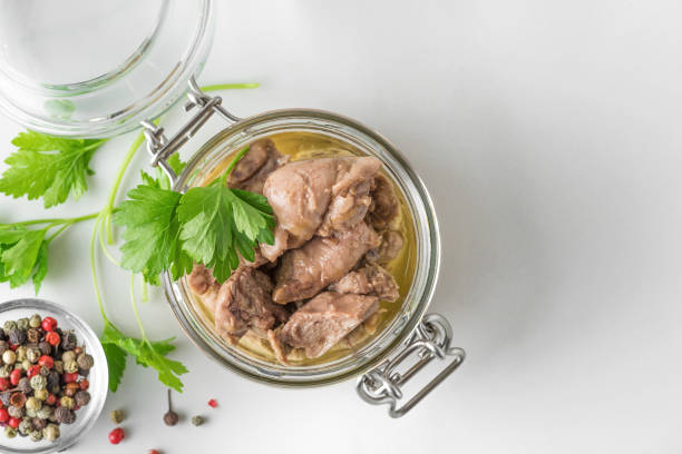 Cod liver in a jar with parsley and pepper on white background. Natural source of omega 3 and vitamin D. top view