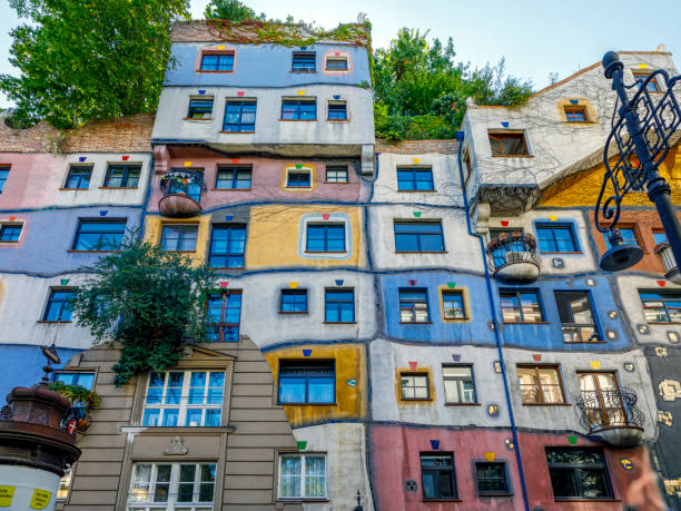 Hundertwasserhaus in Landstrabe District, Vienna City, Austria Vienna, Austria  - September 16, 2019:  Hundertwasserhaus apartment block has colorful facade, undulating floors, roof covered with earth and grass, large trees growing from inside the rooms hundertwasser house stock pictures, royalty-free photos & images