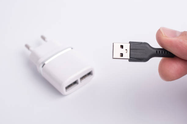 istock White charger for smartphone and black usb cable in hand. 1197699434