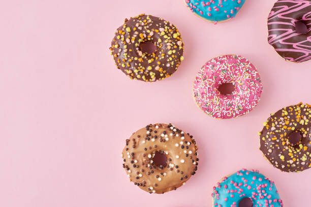 istock Pattern with different types of colorful donats decorated sprinkles and icing on a pastel pink background, top view flat lay 1197700435