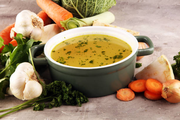 istock Broth with carrots, onions various fresh vegetables in a pot - colorful fresh clear spring soup. Rural kitchen scenery vegetarian bouillon stock 1197704151