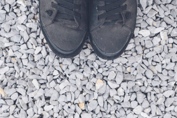 Standing on blue gravel stone ground, worn black sneakers from above with copy space, selective focus