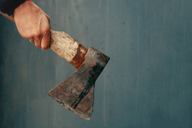 Axe in male hand over old dirty wall