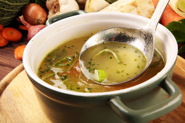 istock Broth with carrots, onions various fresh vegetables in a pot - colorful fresh clear spring soup. Rural kitchen scenery vegetarian bouillon stock 1197706621