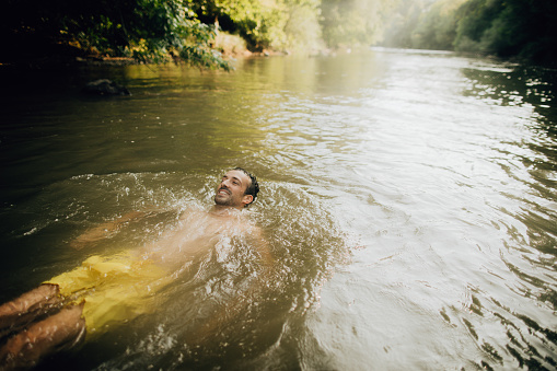 Photo of young man swimming in the lake on a hot summer day