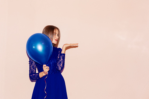 young  and beautiful girl in blue dress holds air balloons. valentines day, birthday, women's day, anniversary, holiday celebration concept