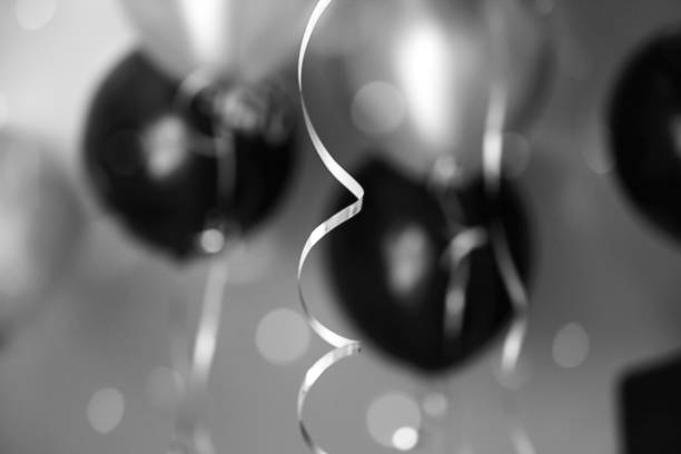 istock Silver ribbon on a background of black and silver balls. Bokeh effect, blurred background. Holiday concept, black and white. View from below. 1197714281