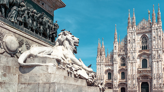 Panoramic view of the Milan city center with sculpture of lion in summer, Italy. Famous Milan Cathedral (Duomo di Milano) in background. Gothic Milan Cathedral is a top landmark of Milan.