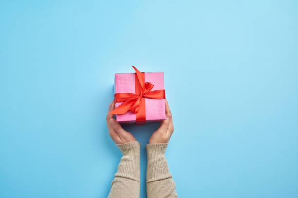 istock two female hands in a sweater hold closed square pink box with a bow 1197724852