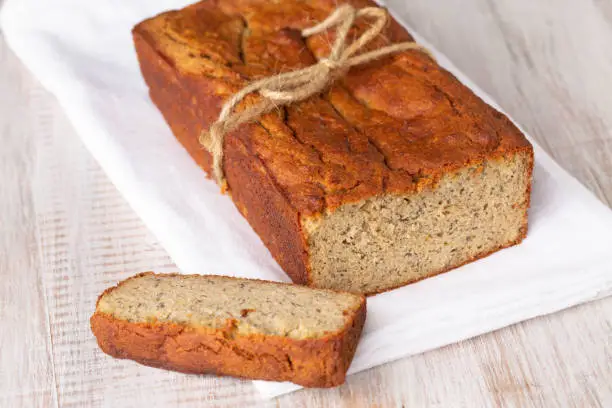 Loaf of gluten free banana bread baked with almond flour on white napkin and background