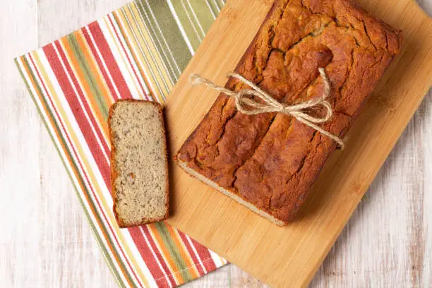 Pretty loaf of gluten free healthy diet banana bread on wood cutting board with napkin