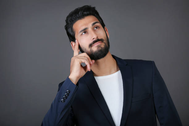 istock Handsome young man looking thoughtfully at isolated grey background with copy space 1197725807