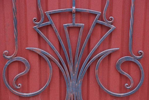gray red texture of iron forged rods in the pattern on the metal wall of the fence