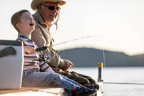 grandfather and grandson fishing at sunset in summer - fishing active seniors family senior adult imagens e fotografias de stock