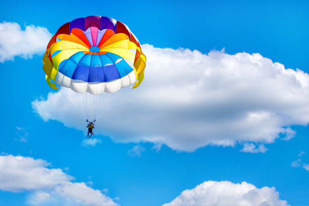 istock A man is gliding using a parachute on the background of cloudy blue sky. 1197731760