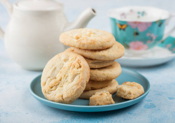 istock White chocolate biscuit cookies on blue ceramic plate with tea pot and cup on blue kitchen table background. 1197731820