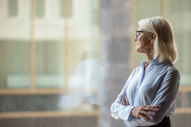 geschäftsfrau mittleren alters in distanz denken oder visualisieren - looking through window window business women stock-fotos und bilder