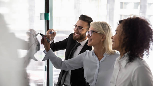 istock Smiling diverse colleagues brainstorm writing on whiteboard 1197735224