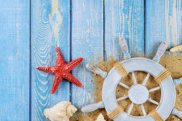 istock Captain steering wheel on shells and starfish on rustic border 1197744394