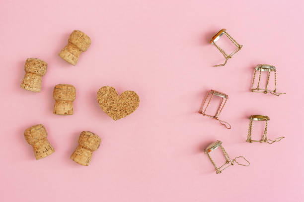 Creative layout with corks and muselets from champagne and heart on pink paper with copy space. Background for Birthday, party, wedding. Hen-party greeting card.