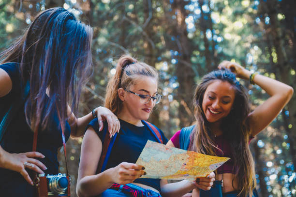 istock Female friends trying to find right path on map in forest 1197752391