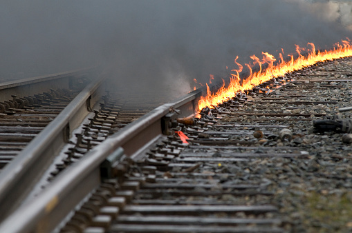 Train tracks interchange leading around a curve as a controlled fire burns on the track during repairs