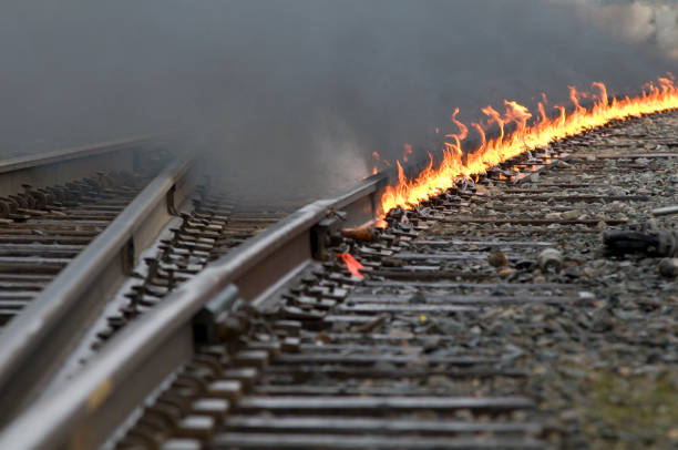 fire on the train tracks interchange leading around a curve - railroad spikes imagens e fotografias de stock