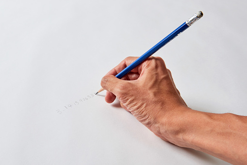Man writing pi with pencil on paper