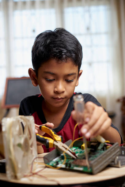 Schoolboy repairing electronic computer part at home stock photo