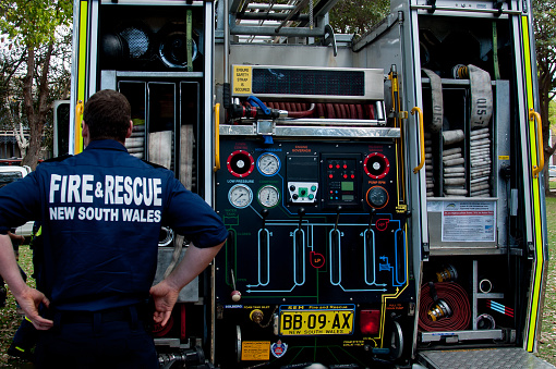 Sydney, Australia - 2014-09-21. Fire and Rescue New South Wales crew member standing near the open back of a fire truck