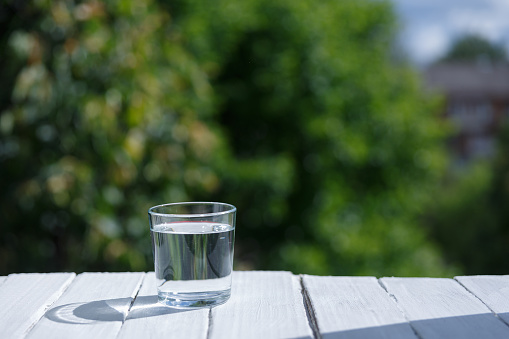 A glass with clean drinking water, a natural green floral background.