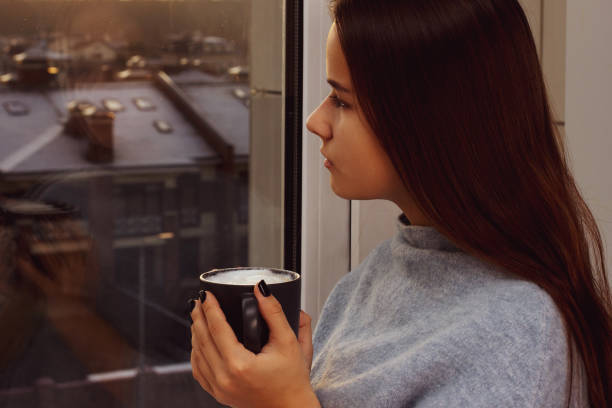 istock Nice girl drinks coffee and looks out the window at sunset 1197790879