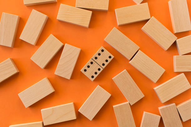 istock Playing dominoes on a orange table. Leisure games concept. Domino effect. 1197791032