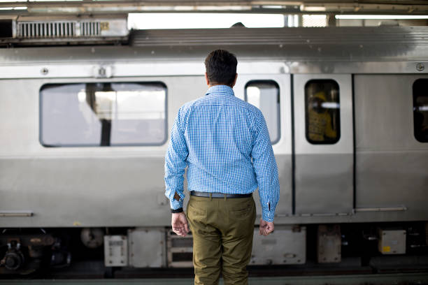 Man standing at railroad station Rear view of man standing at railroad station platform delhi metro stock pictures, royalty-free photos & images