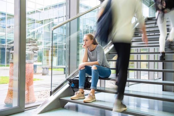 грустная школьница, сидящая одна на лестнице - university education walking teenage girls стоковые фото и изображения