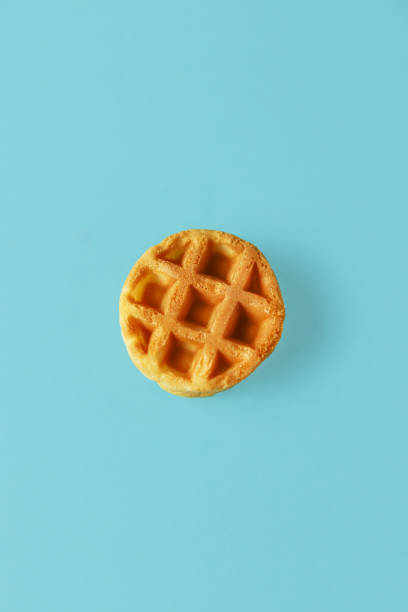 istock Small round Belgian waffle on trendy blue background 1197797434