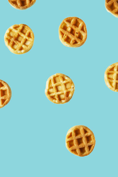 istock Flying small round waffles isolated on trendy blue background 1197797492