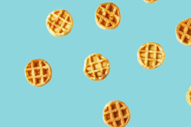 istock Flying small round waffles isolated on trendy blue background 1197797535