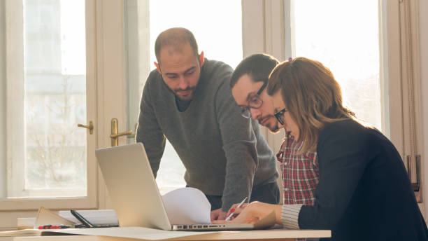 istock Group of young architects in the sunny office. 1197799251