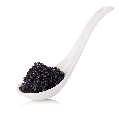 Spoon with black sturgeon caviar isolated on a white background.