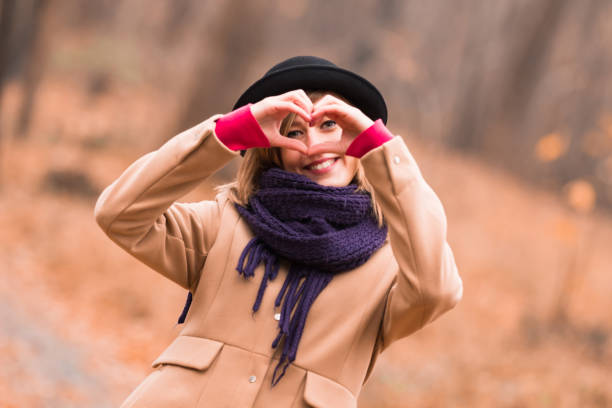 joven mujer al aire libre haciendo corazón - símbolo de forma para el amor y el romance. - heart shape loneliness women praying fotografías e imágenes de stock