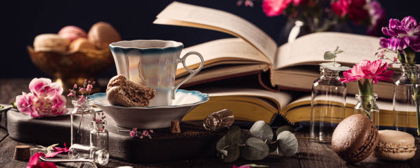 Cup of coffee, old books and pink carnation flowers
