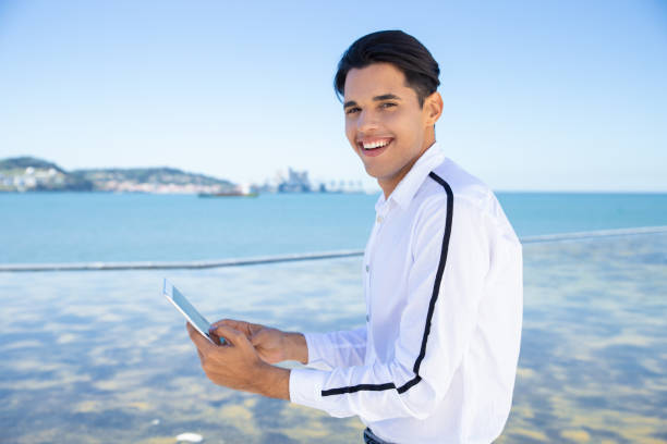 istock Smiling young man using tablet outdoors 1197815106