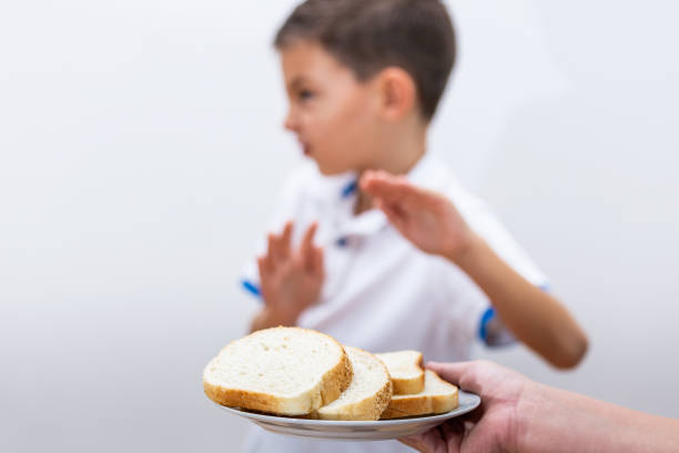 グルテン不耐症とダイエットコンセプト。子供は白いパンを食べるのを拒否する。パンに選択的な焦点。グルテンフリーダイエットの子供はトーストのおかげでノーと言っています。 - food white caucasian color image ストックフォトと画像