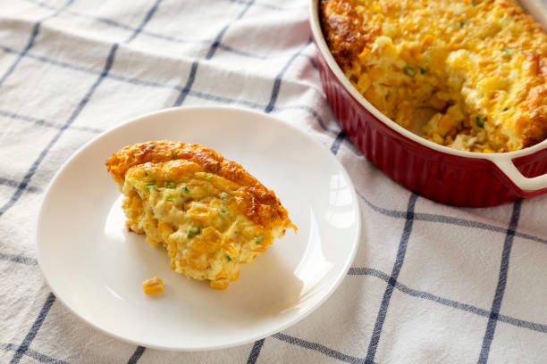 istock Homemade Cheddar Corn Pudding Casserole on a white plate, low angle view. Closeup. 1197821411