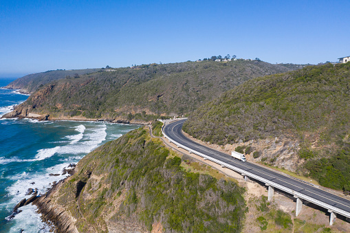 Aerial image of a truck driving along a coastal highway overlooking the sea. Kaaiman's river mouth, South Africa