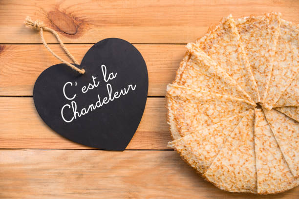 Top view of crepes (french pancakes), text c'est la chandeleur in a heart, rustic wood background Top view of crepes (french pancakes), text c'est la chandeleur in a heart, rustic wood background candlemas stock pictures, royalty-free photos & images